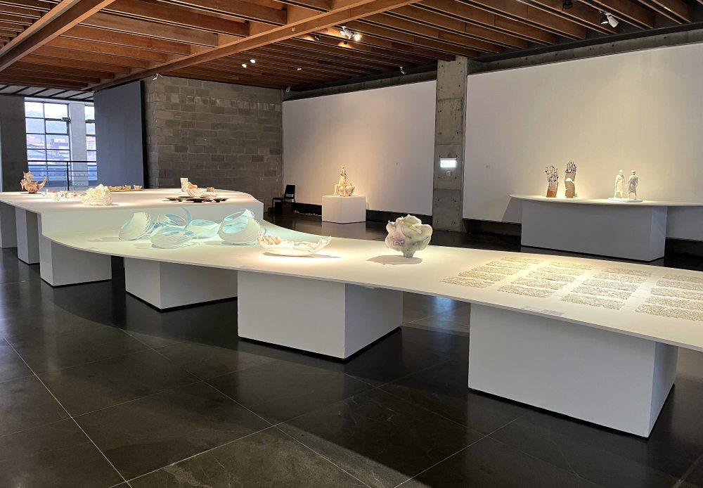 展覽現場以曲形為輪廓處理中央大檯面，帶動觀者動線，並以微幅高低差引導視線流轉