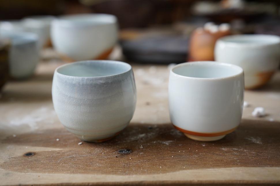林文雄2025年於寶來柴窯燒製作的兩件青瓷杯，左圖無使用匣缽、右圖放入匣缽中燒製，產生不一樣釉彩變化。（馬嘉伸攝影）